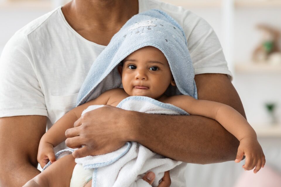 Infant baby in towel relaxing in father's arms